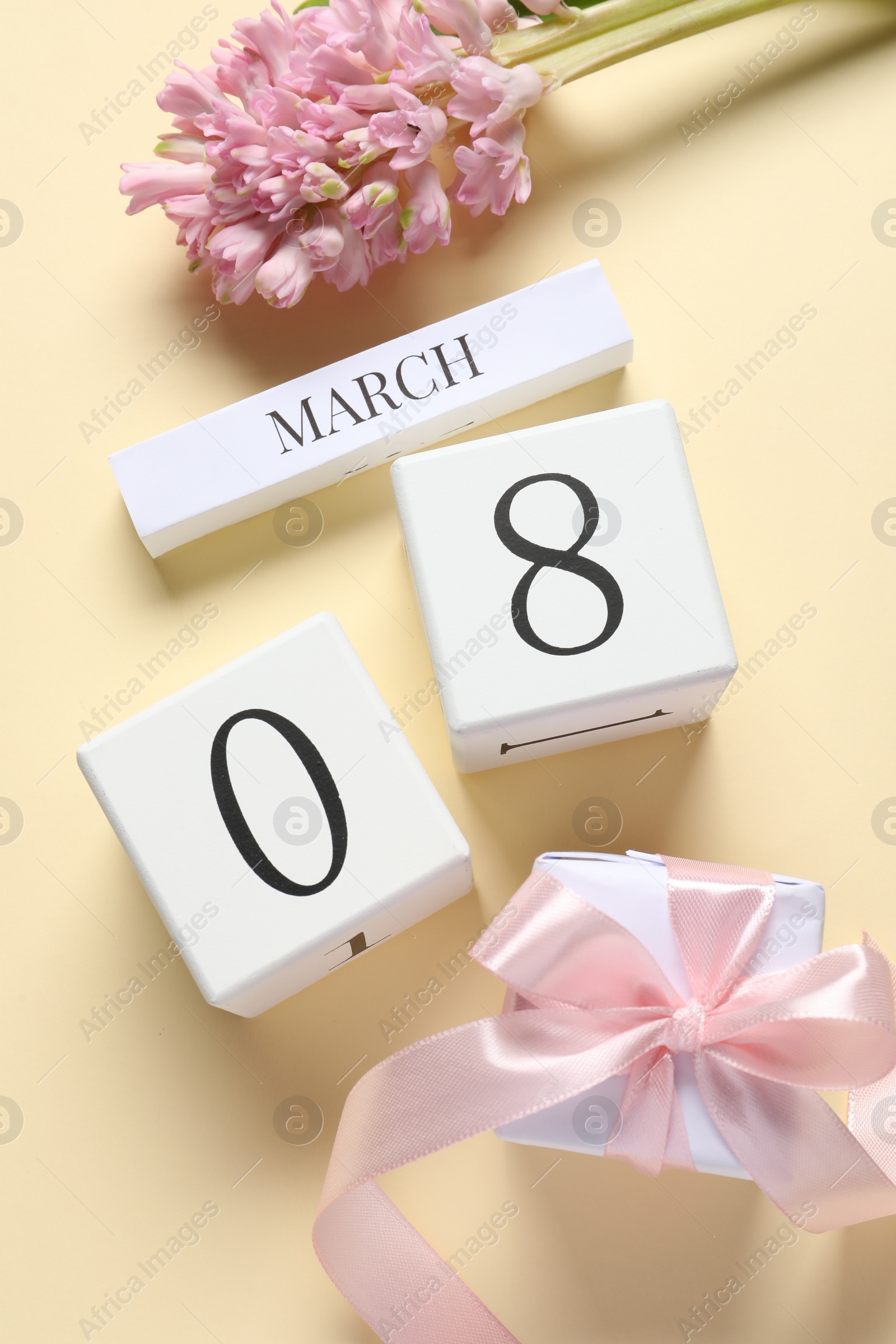 Photo of International Women's day - 8th of March. Gift box, wooden block calendar and beautiful flowers on beige background, flat lay