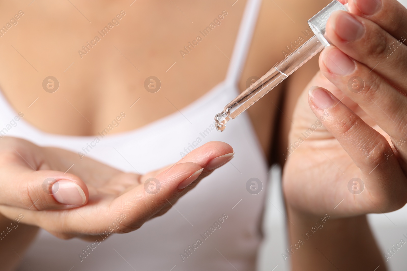 Photo of Woman applying cosmetic serum onto her finger, closeup