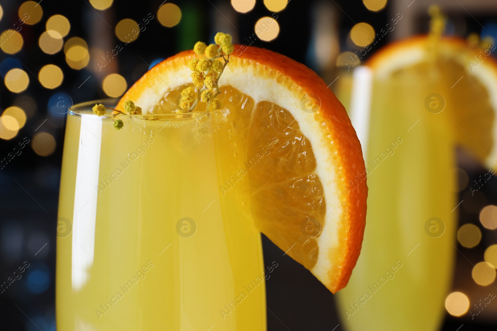 Photo of Mimosa cocktail with garnish against blurred lights, closeup