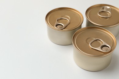 Photo of Tin cans with wet cat food on white background. Space for text
