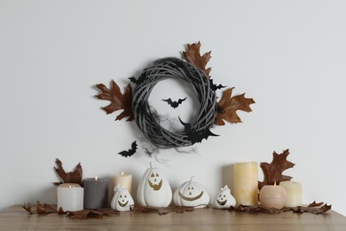 Photo of Different pumpkin shaped holders, autumn leaves and burning candles on wooden table. Halloween decor