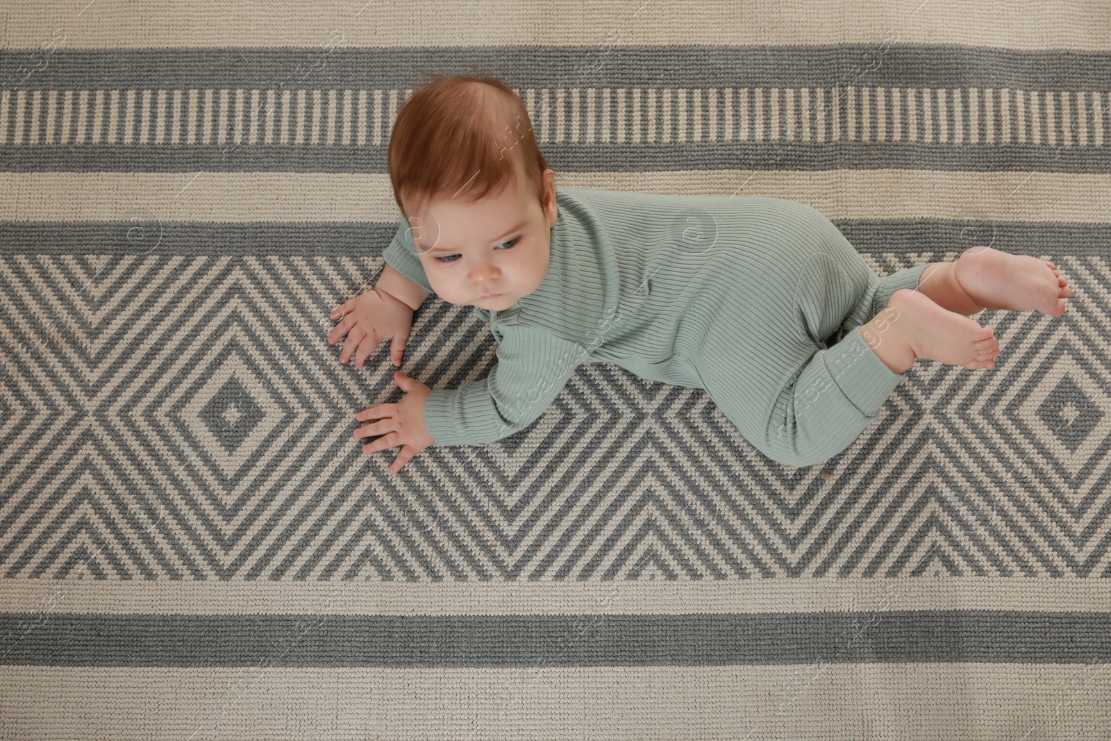 Photo of Cute baby crawling on floor, top view