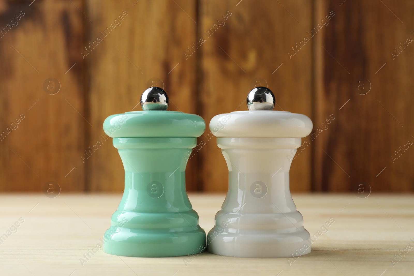 Photo of Salt and pepper shakers on light wooden table, closeup