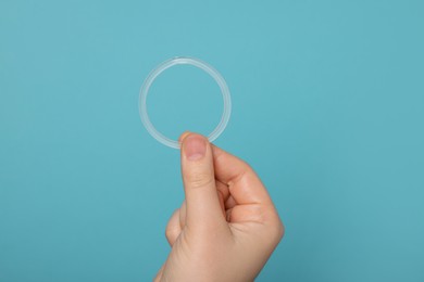 Photo of Woman holding diaphragm vaginal contraceptive ring on light blue background, closeup