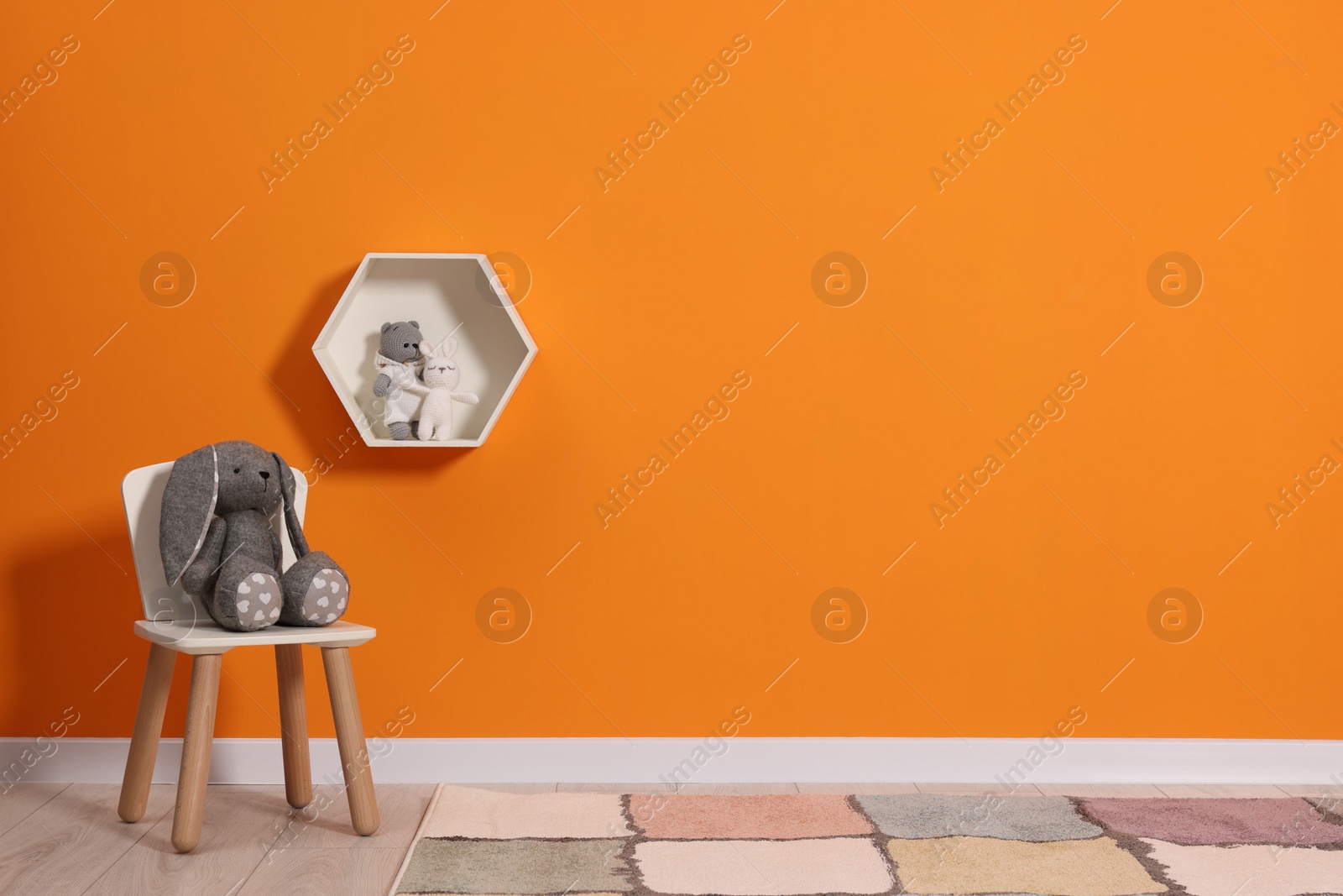 Photo of Beautiful children's room with bright orange wall and furniture, space for text. Interior design