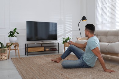 Photo of Man watching television at home. Living room interior with TV on stand