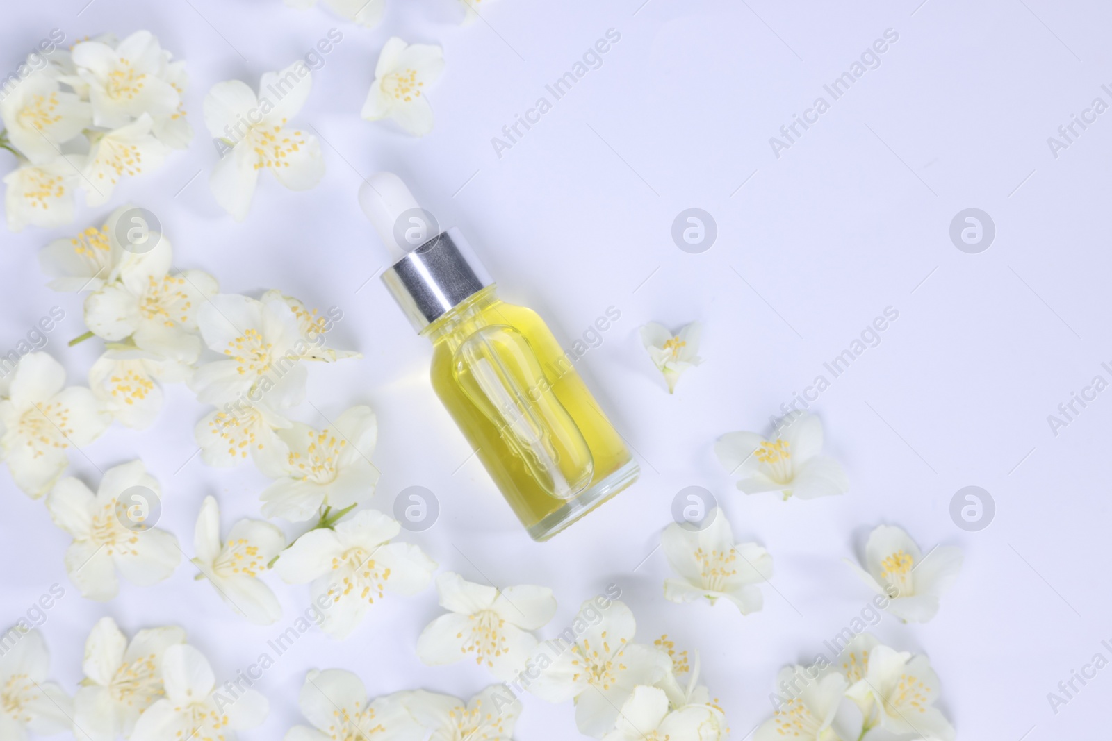 Photo of Essential oil in bottle and beautiful jasmine flowers on white background, flat lay. Space for text