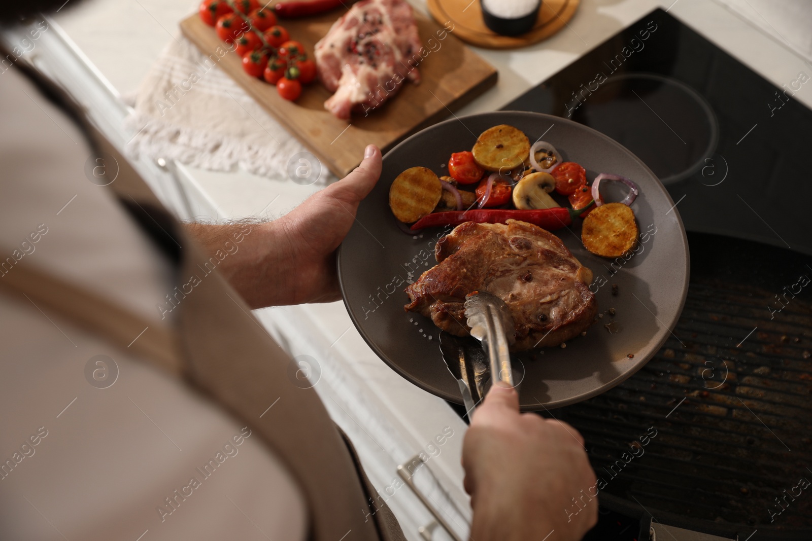 Photo of Man with tasty meat and vegetables cooked on frying pan, above view
