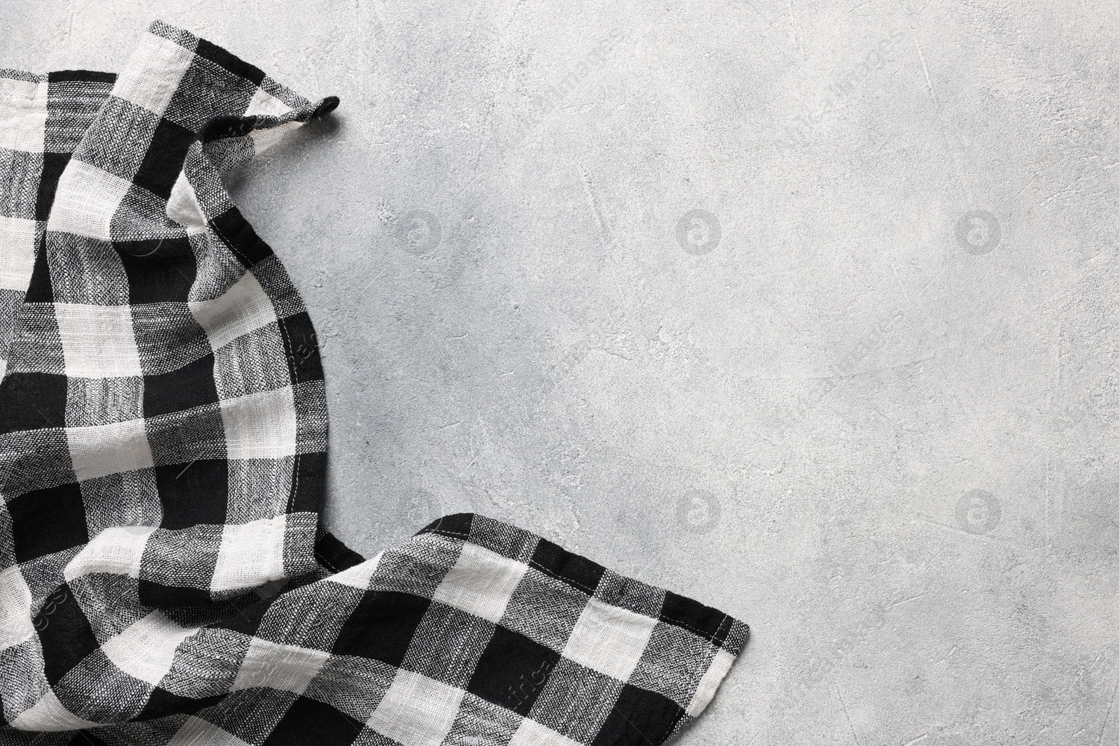 Photo of Black checkered tablecloth on light gray textured table, top view. Space for text