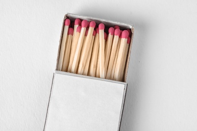 Photo of Cardboard box with matches on light background, top view. Space for design