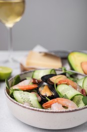 Photo of Bowl of delicious salad with seafood on light grey table, closeup