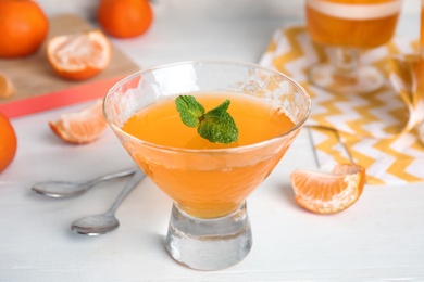 Photo of Delicious tangerine jelly in glass on white wooden table, closeup