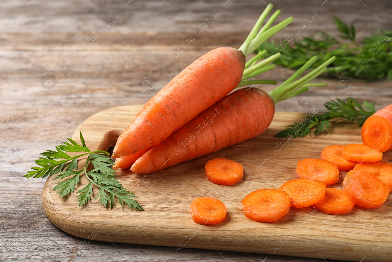 Photo of Board with cut carrot on wooden background