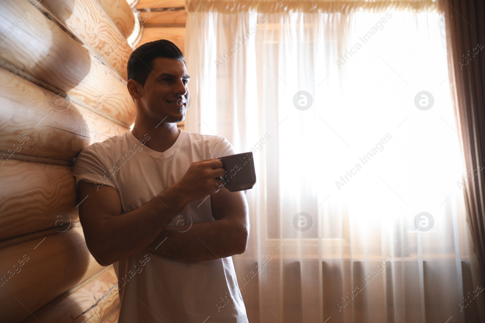 Photo of Man with drink near window indoors. Lazy morning