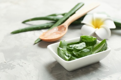 Photo of Bowl with sliced aloe vera leaves on gray table