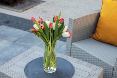 Beautiful bouquet of colorful tulips on rattan garden table outdoors