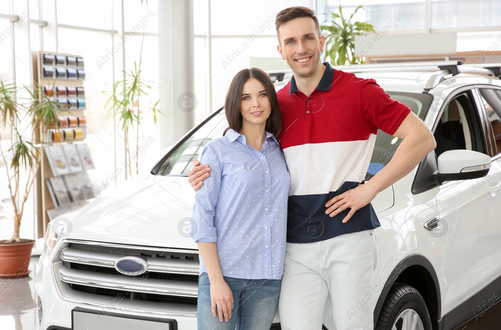 Photo of Young couple near auto in salon. Buying new car