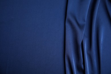 Photo of Crumpled dark blue silk fabric as background, top view. Space for text