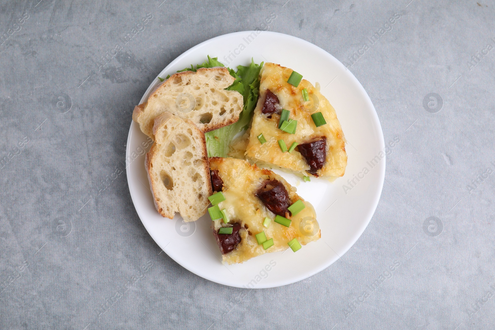 Photo of Tasty sausage casserole with green onion and bread on grey table, top view