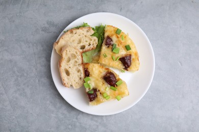 Photo of Tasty sausage casserole with green onion and bread on grey table, top view