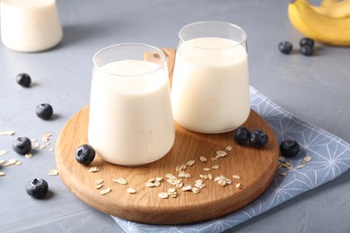 Tasty yogurt in glasses, oats and blueberries on grey table