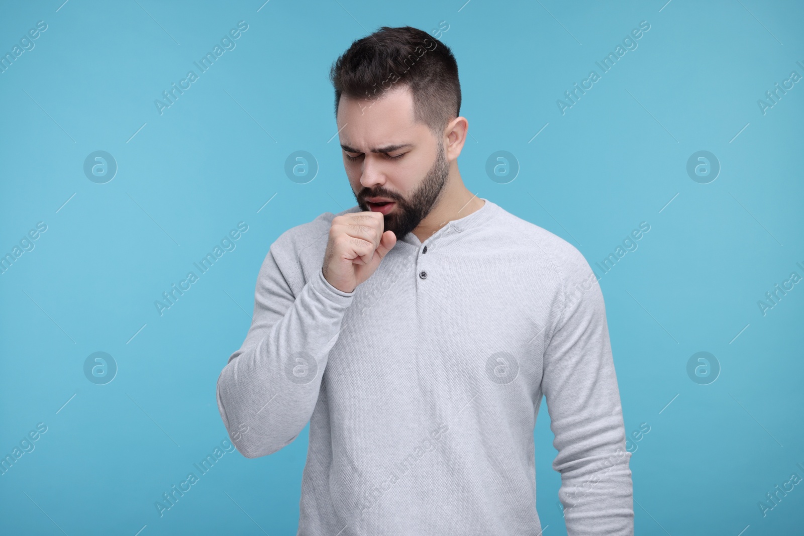 Photo of Sick man coughing on light blue background