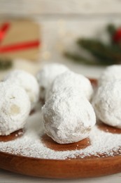 Wooden plate with Christmas snowball cookies on table, closeup