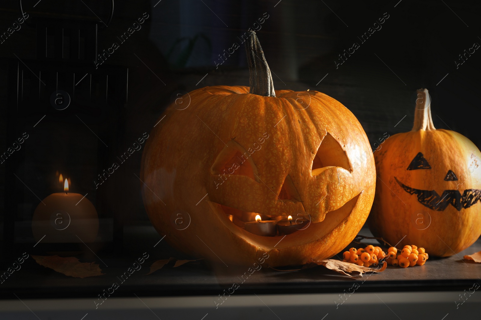 Photo of Halloween pumpkin heads. Jack lanterns on windowsill, view through glass