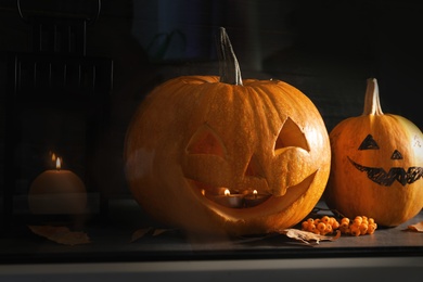 Halloween pumpkin heads. Jack lanterns on windowsill, view through glass