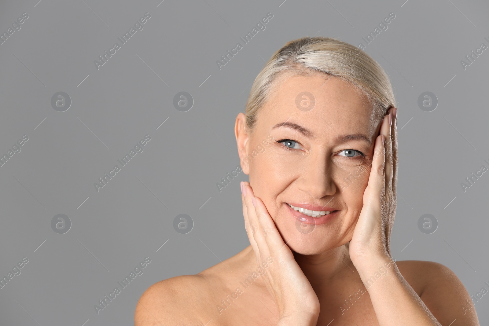 Photo of Portrait of beautiful mature woman on grey background. Space for text