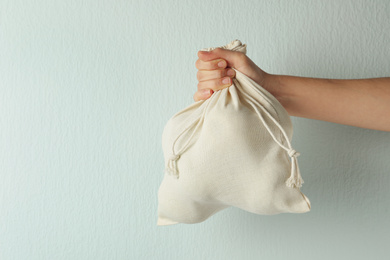 Photo of Woman holding full cotton eco bag on light background, closeup