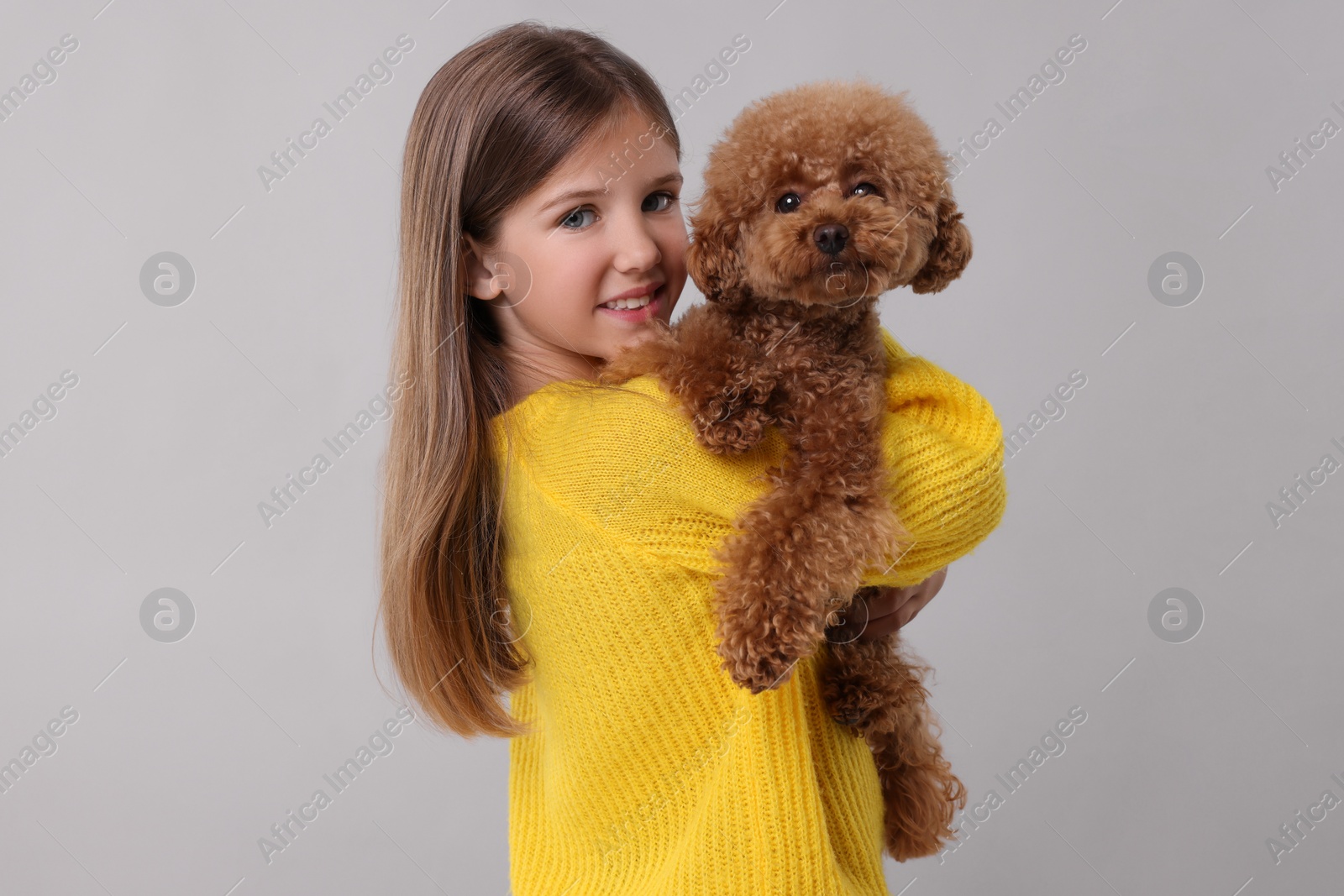 Photo of Little child with cute puppy on light grey background. Lovely pet