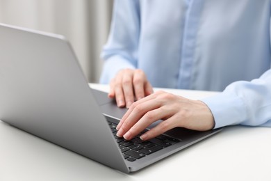 E-learning. Woman using laptop at white table indoors, closeup