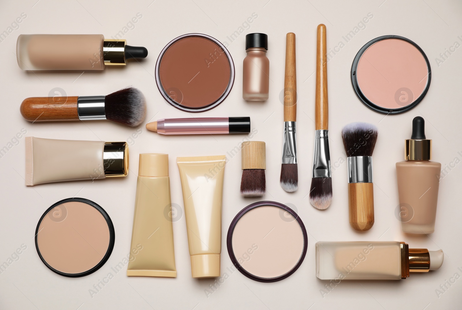 Photo of Face powders and other makeup products on beige background, flat lay