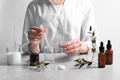 Photo of Scientist making cosmetic product at grey table in laboratory, closeup