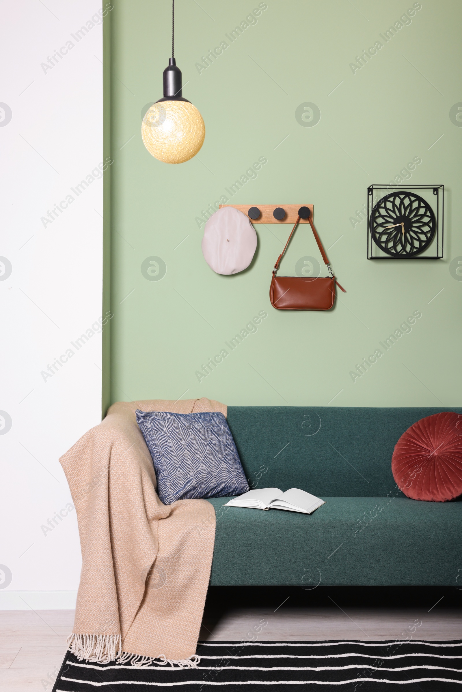 Photo of Stylish interior with comfortable sofa, blanket and cushions