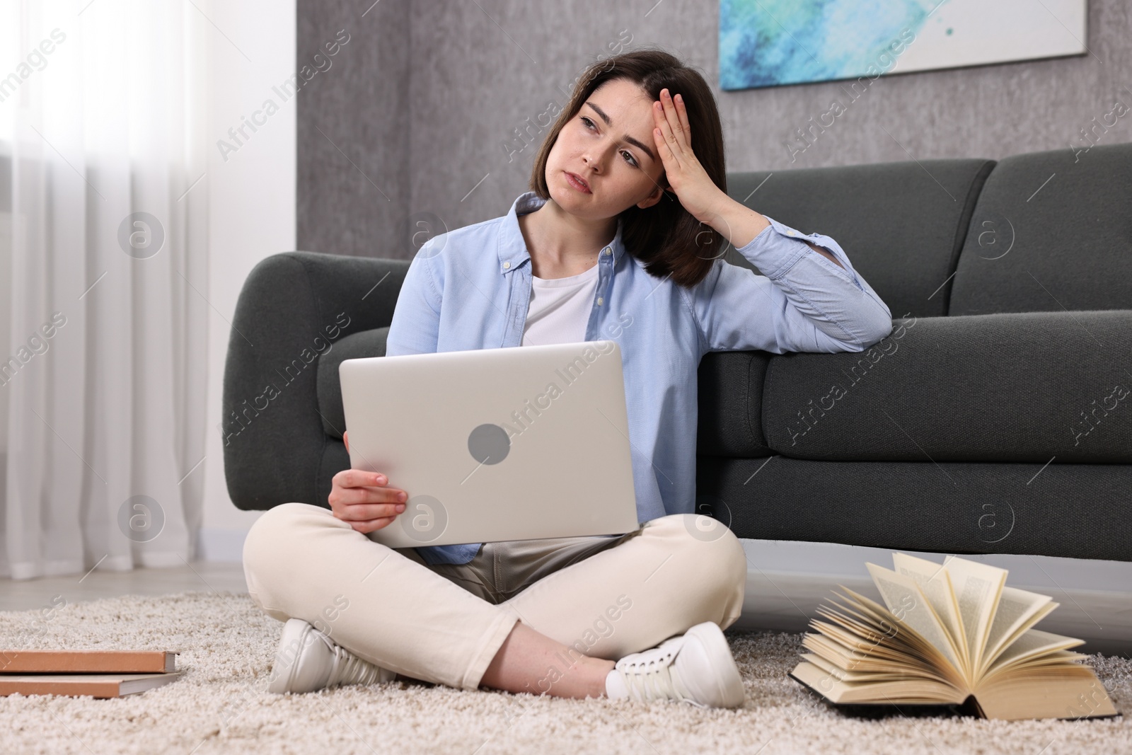 Photo of Overwhelmed woman with laptop sitting on floor indoors