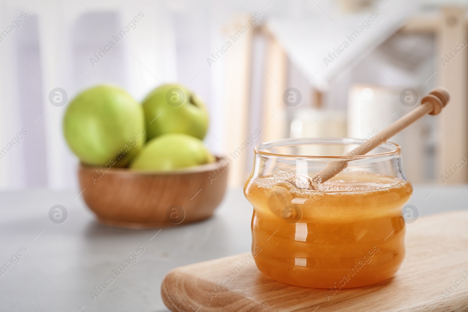 Photo of Jar of honey, apples and dipper on light table