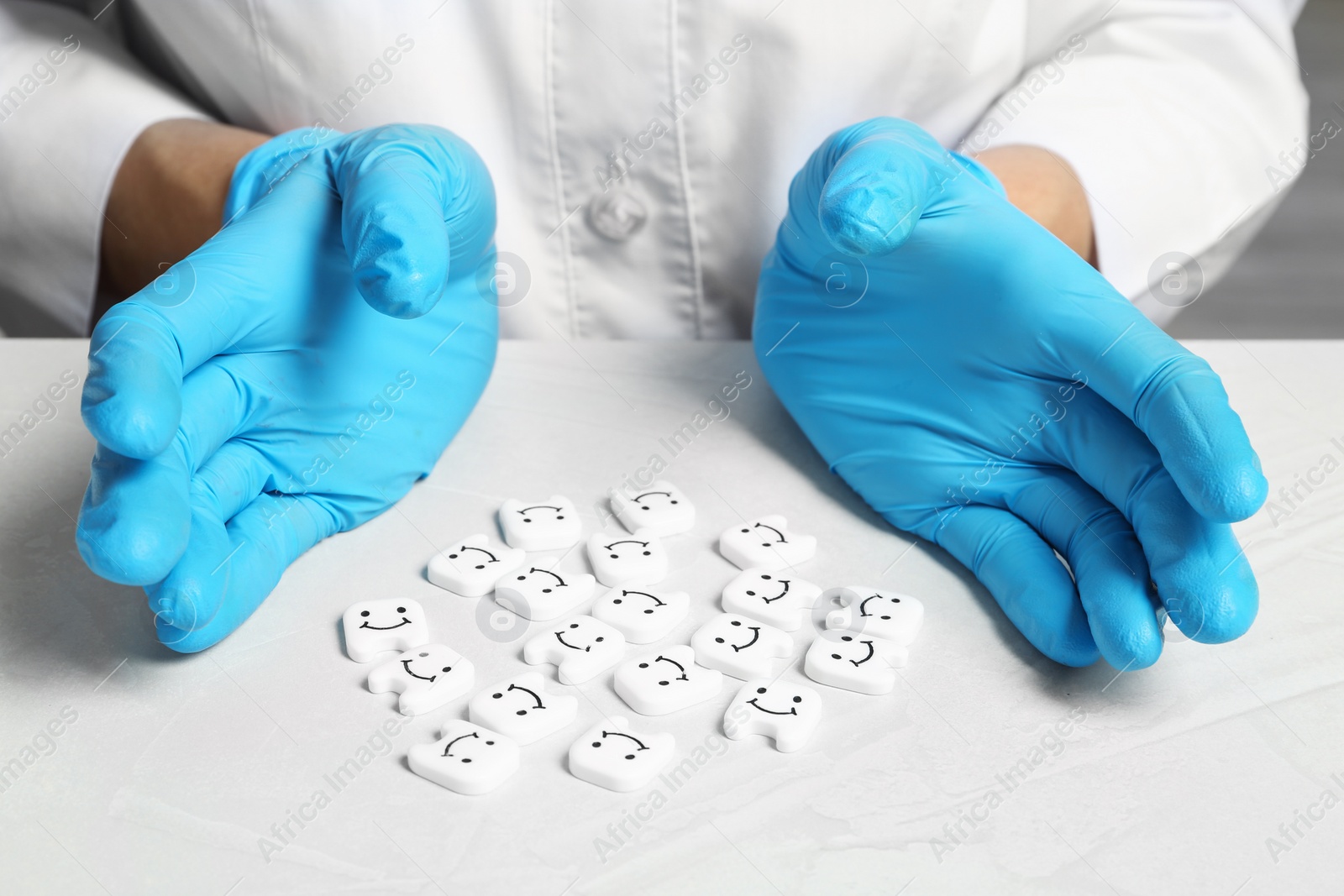 Photo of Dentist holding hands near small plastic teeth on table, closeup