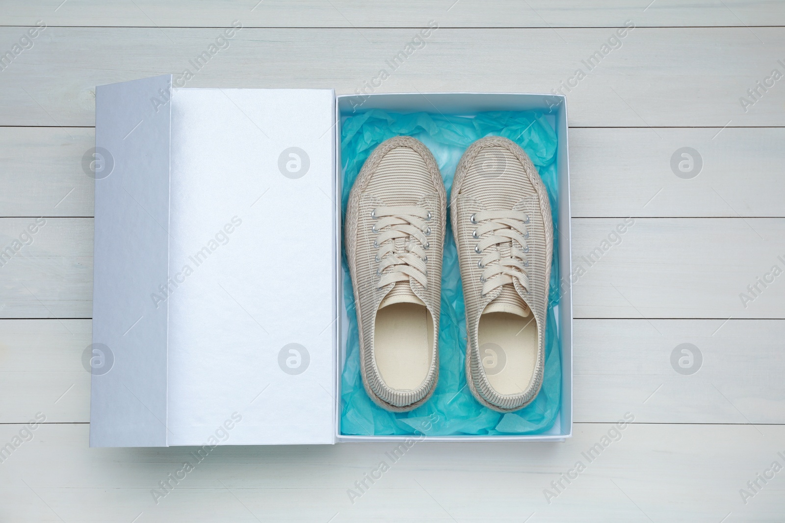 Photo of Pair of stylish sport shoes in box on white wooden background, top view
