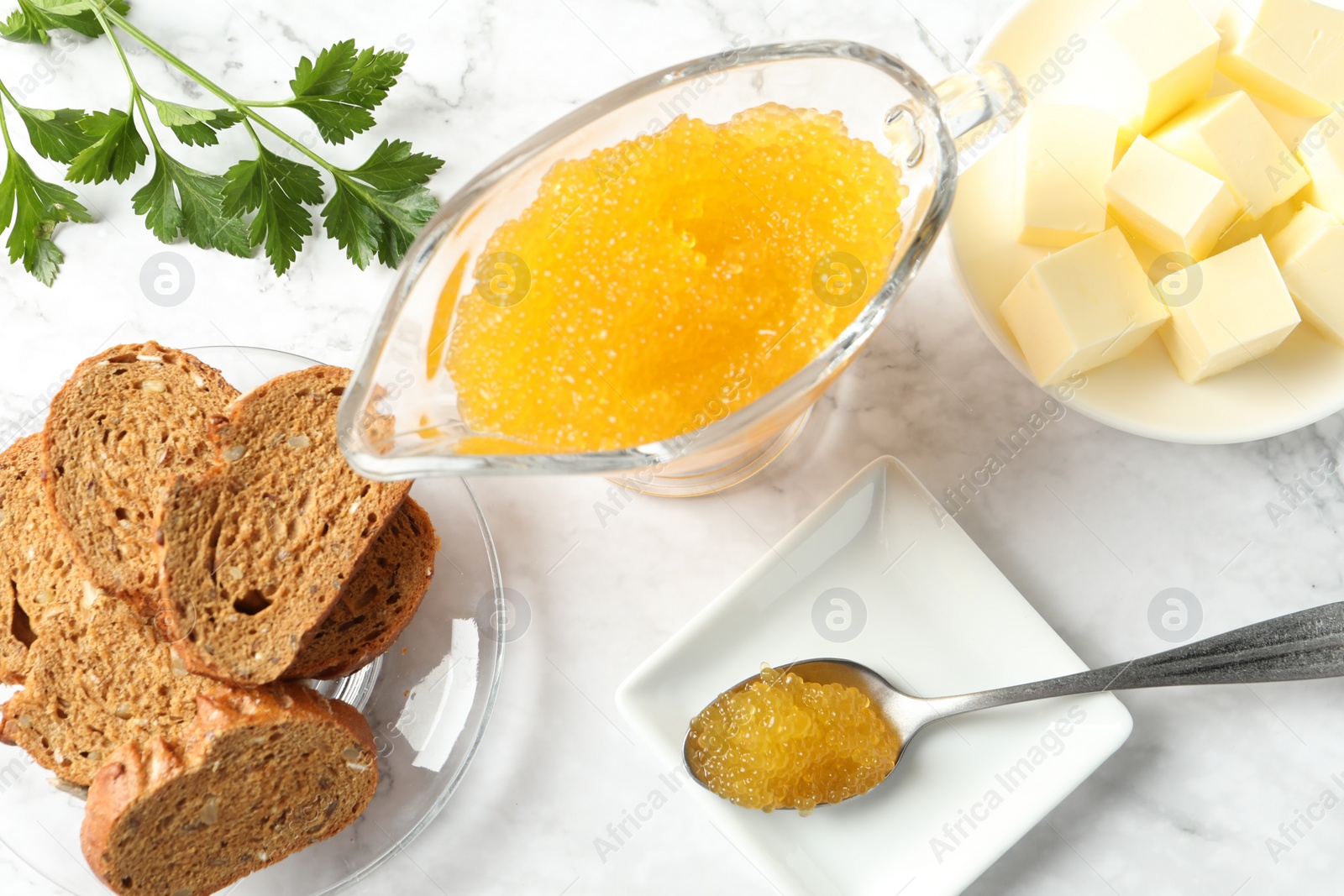 Photo of Fresh pike caviar, butter, bread and parsley on white marble table, flat lay