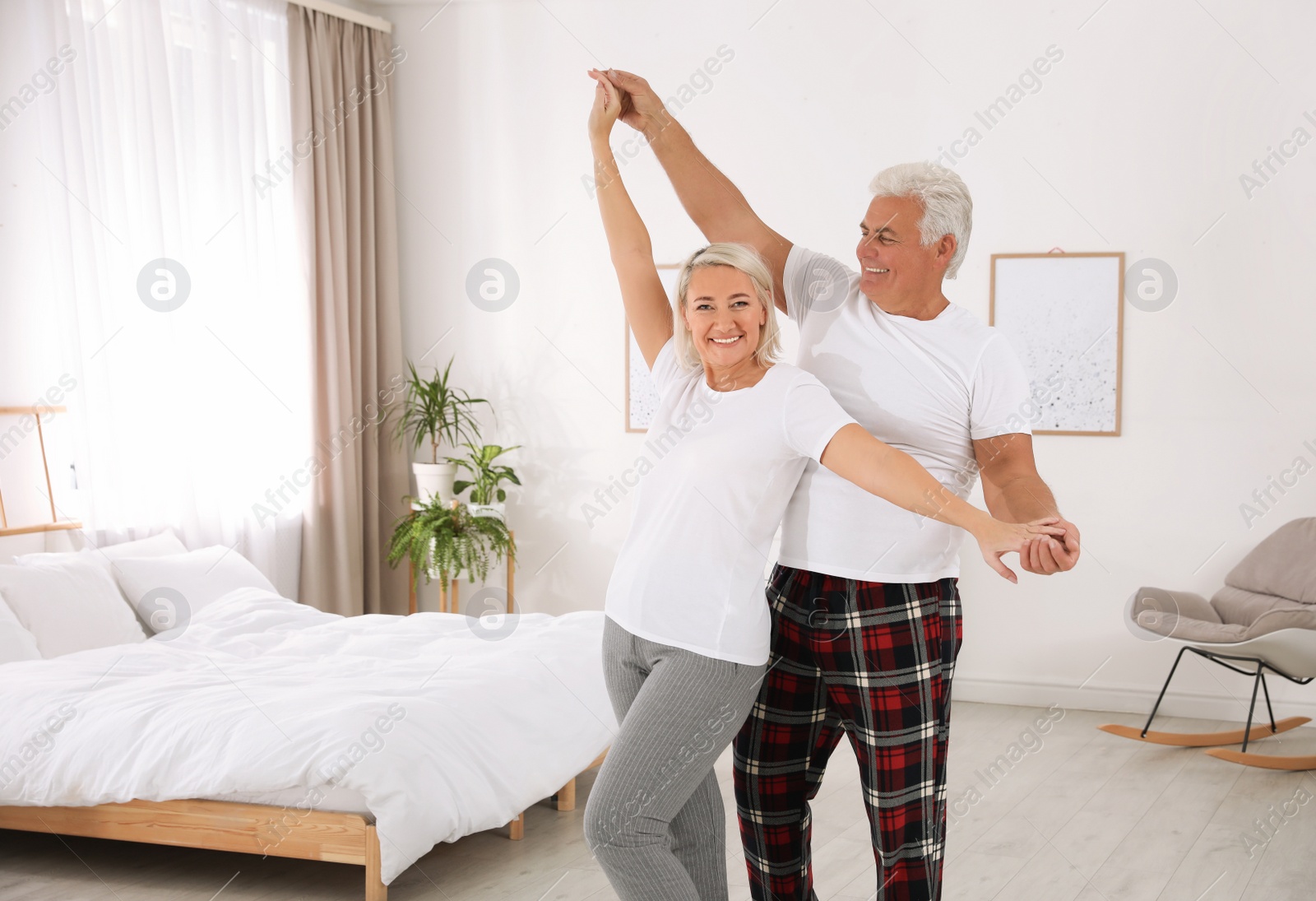 Photo of Happy mature couple dancing together in bedroom