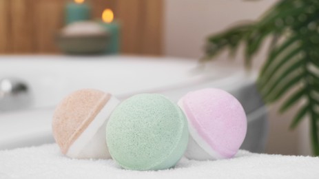 Photo of Colorful bath bombs on white towel in bathroom, closeup