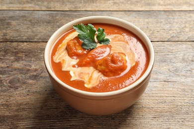 Photo of Bowl of delicious butter chicken on wooden table. Traditional indian Murgh Makhani
