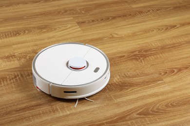 Robotic vacuum cleaner on wooden floor, space for text