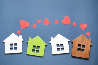 Photo of Long-distance relationship concept. House models and paper hearts on blue background, flat lay