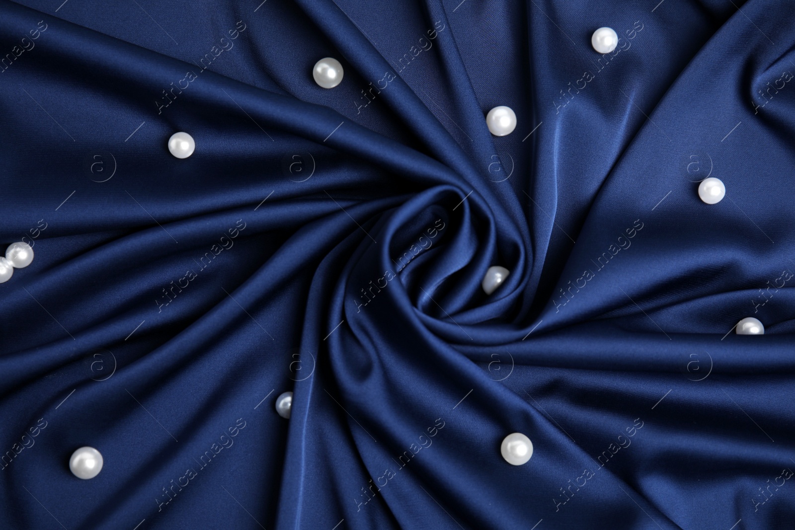 Photo of Many beautiful pearls on delicate dark blue silk, flat lay