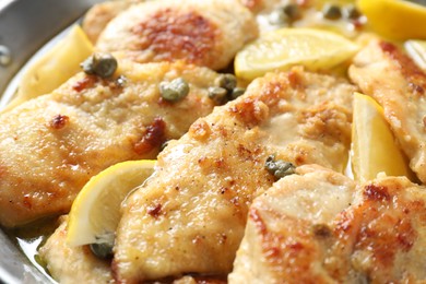 Photo of Delicious chicken piccata with lemons as background, closeup