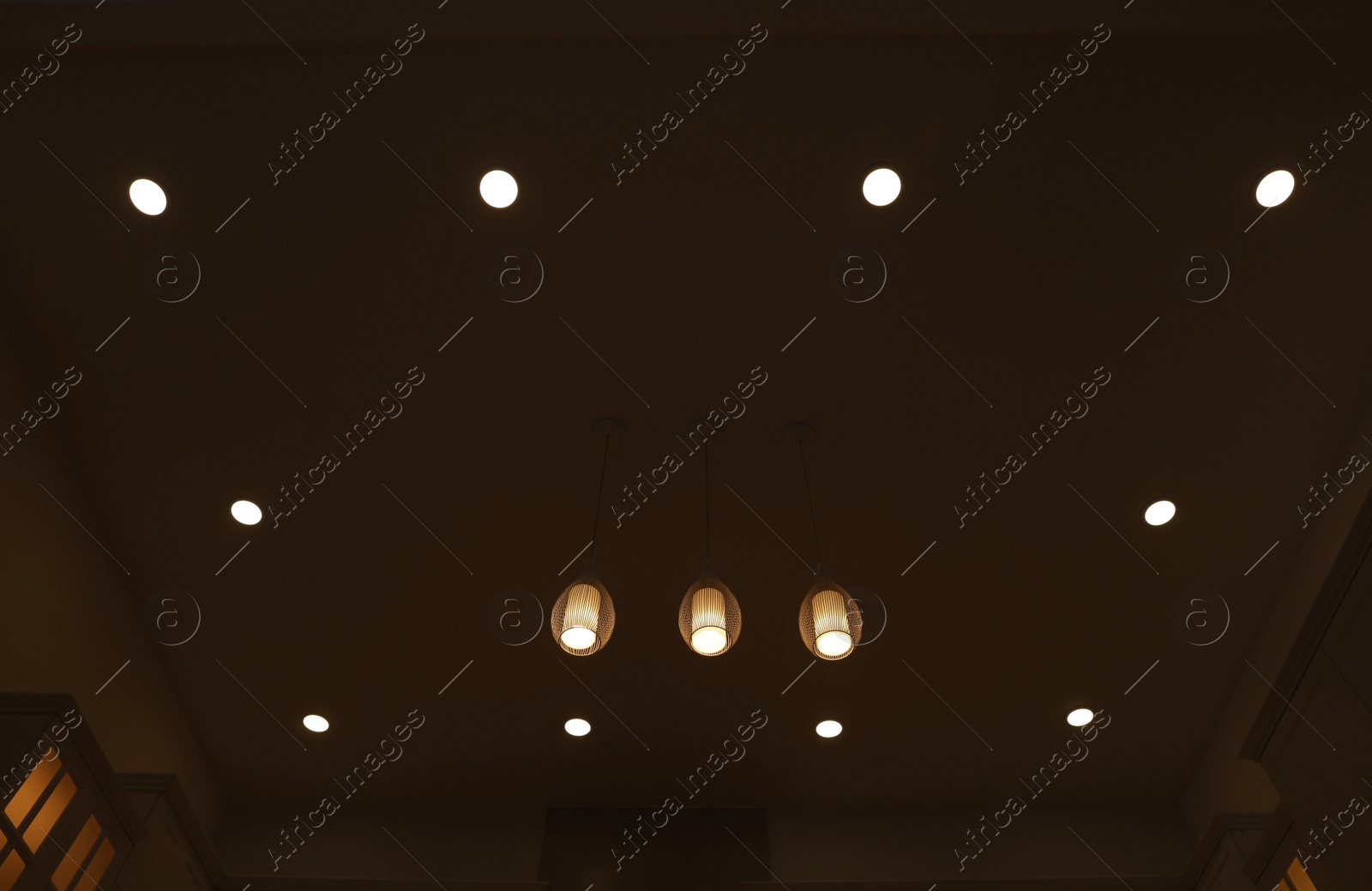 Photo of Ceiling with modern lamps in stylish room at night, low angle view