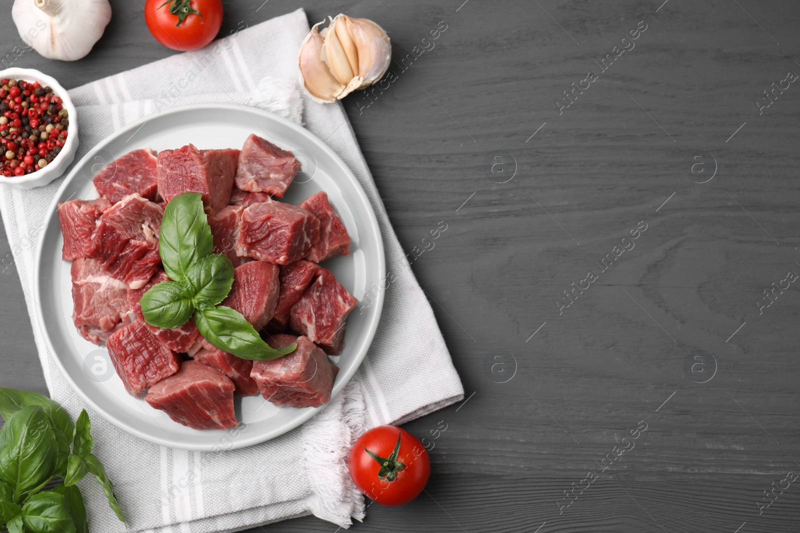 Photo of Flat lay composition with cut fresh beef meat on grey wooden table. Space for text